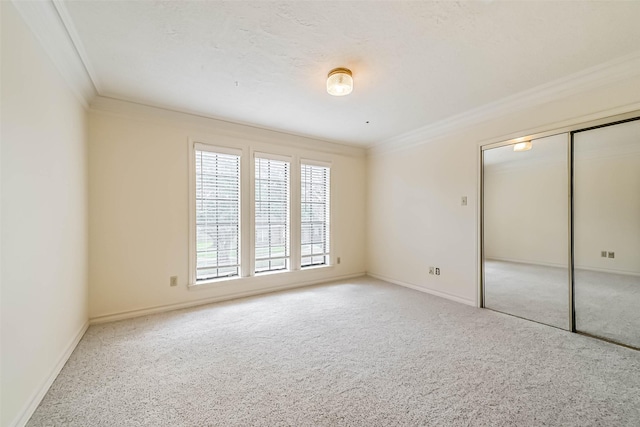 unfurnished bedroom featuring carpet floors, ornamental molding, a closet, and baseboards