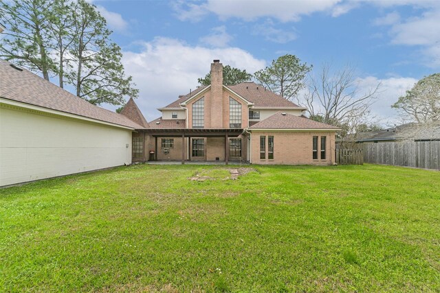 back of house featuring a fenced backyard, a chimney, a lawn, and a patio