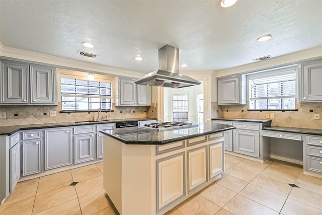 kitchen featuring light tile patterned flooring, island range hood, a kitchen island, a sink, and visible vents