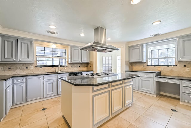 kitchen with a wealth of natural light, a sink, visible vents, island range hood, and a kitchen island