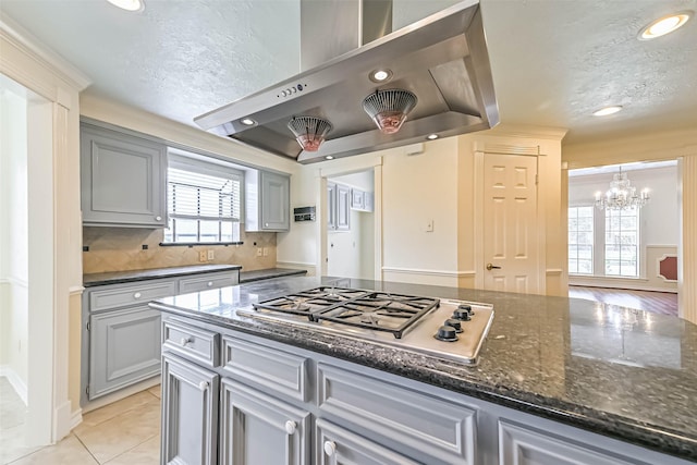 kitchen featuring a textured ceiling, recessed lighting, a chandelier, stainless steel gas stovetop, and wall chimney range hood
