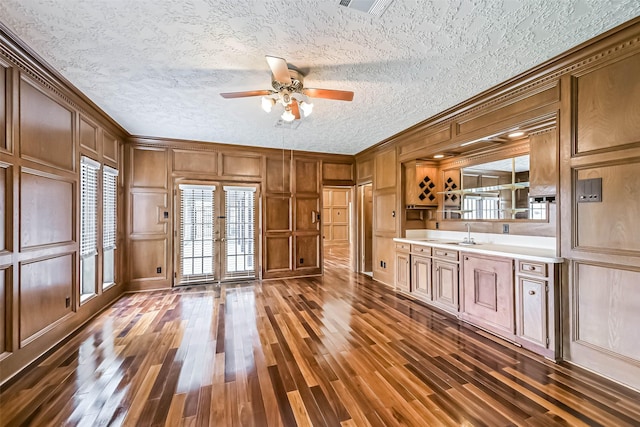 interior space with light countertops, a decorative wall, crown molding, and dark wood-style flooring