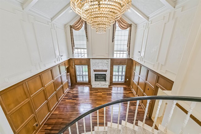 interior space with dark wood finished floors, a decorative wall, a tiled fireplace, an inviting chandelier, and stairs