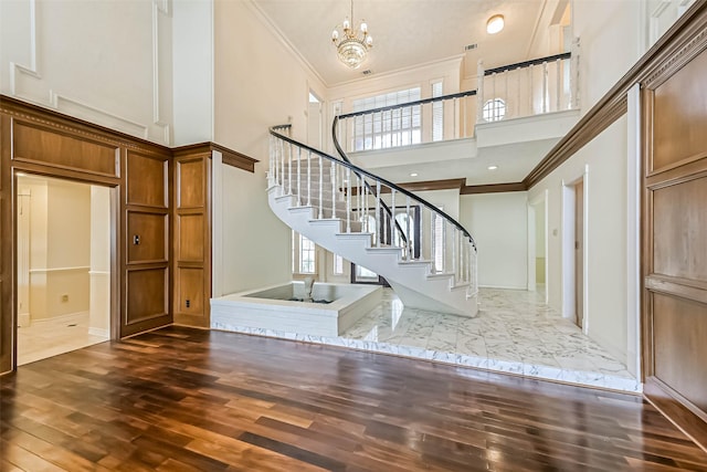 entryway with a notable chandelier, dark wood finished floors, stairway, a high ceiling, and ornamental molding