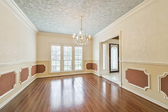 unfurnished dining area with wainscoting, crown molding, dark wood-style flooring, and a chandelier