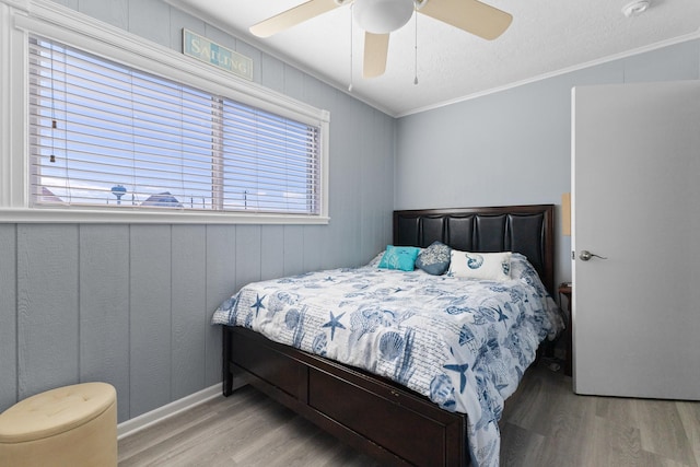 bedroom featuring a ceiling fan, ornamental molding, and wood finished floors