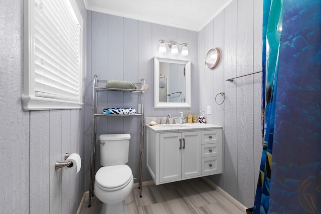 bathroom featuring toilet, ornamental molding, wood finished floors, and vanity