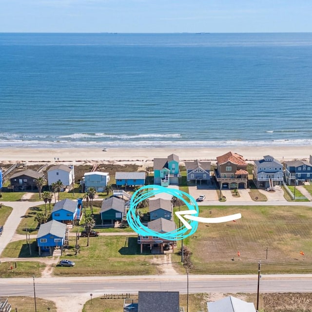 drone / aerial view featuring a water view, a residential view, and a beach view