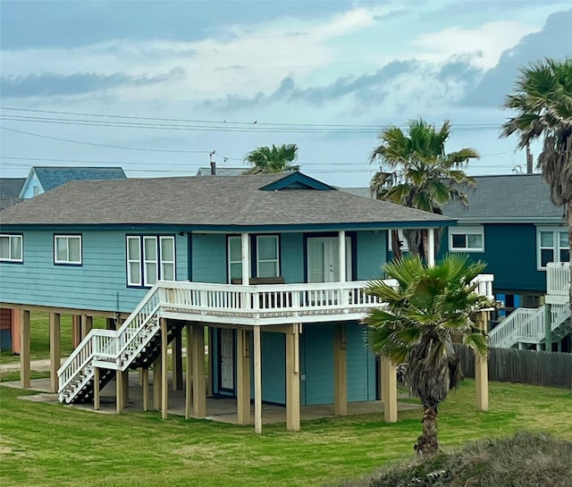 rear view of property with roof with shingles, stairway, and a yard