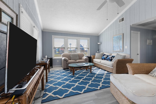 living room with visible vents, lofted ceiling, wood finished floors, a textured ceiling, and crown molding