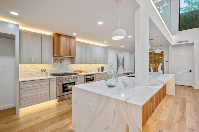 kitchen with recessed lighting, high end stainless steel range oven, backsplash, light wood-type flooring, and beverage cooler