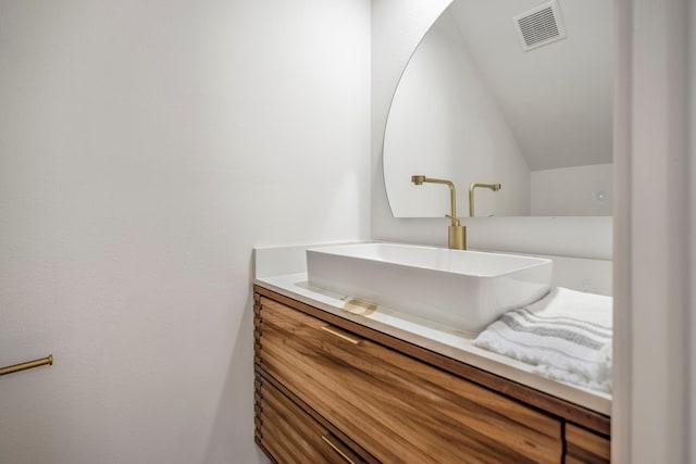 bathroom with visible vents, vaulted ceiling, and vanity