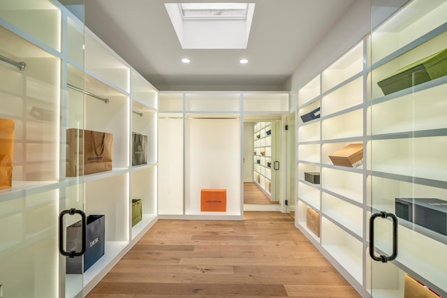 walk in closet with light wood-type flooring and a skylight