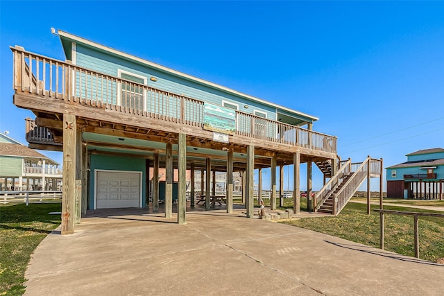 view of front facade featuring a carport, concrete driveway, fence, a garage, and stairs