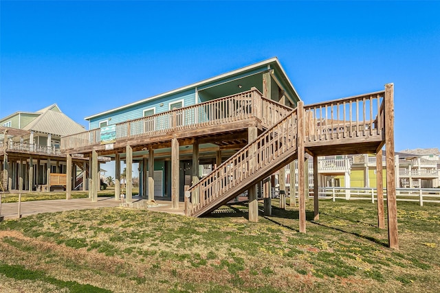 back of property featuring a deck, fence, stairway, and a lawn