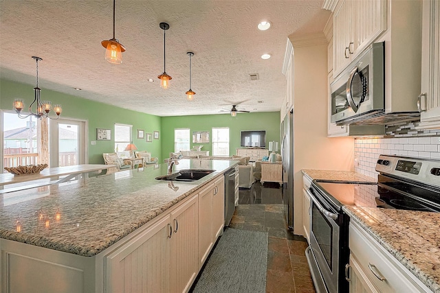 kitchen featuring plenty of natural light, appliances with stainless steel finishes, open floor plan, a sink, and backsplash