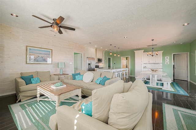 living room with dark wood-style floors, ceiling fan with notable chandelier, a textured ceiling, and recessed lighting