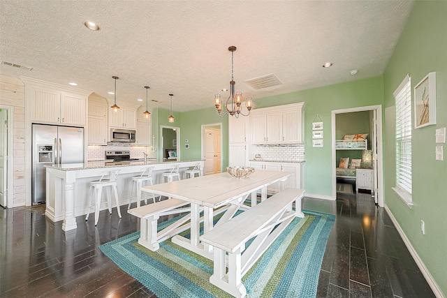 dining space with a healthy amount of sunlight, dark wood-type flooring, visible vents, and an inviting chandelier