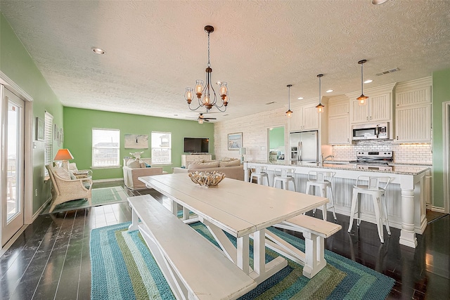 dining area with recessed lighting, visible vents, dark wood-type flooring, a textured ceiling, and a chandelier