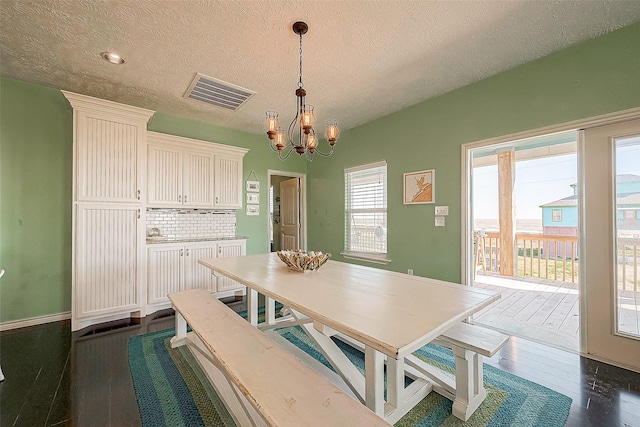 dining area featuring a chandelier, dark wood-style flooring, visible vents, and a textured ceiling