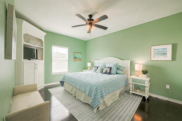 bedroom with ceiling fan, a textured ceiling, wood finished floors, and baseboards