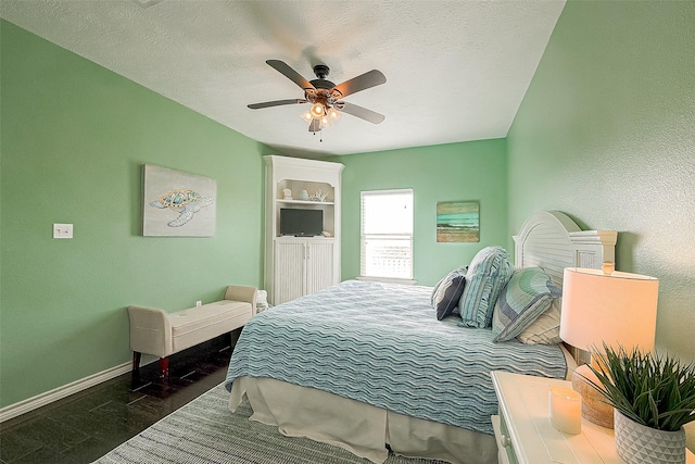 bedroom featuring a textured ceiling, a textured wall, wood finished floors, a ceiling fan, and baseboards