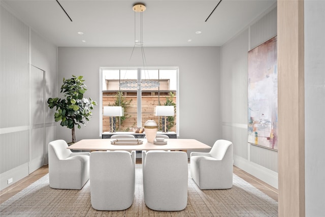 dining room featuring light wood-style flooring, baseboards, a decorative wall, and recessed lighting