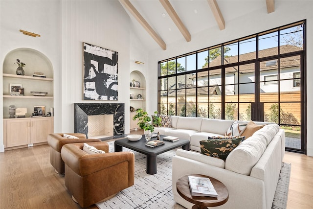 living area with built in features, wood finished floors, beamed ceiling, a fireplace, and high vaulted ceiling