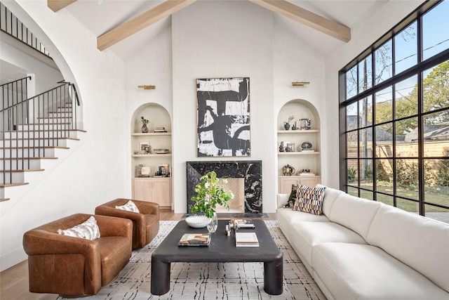 living area with built in features, wood finished floors, stairs, high vaulted ceiling, and beam ceiling