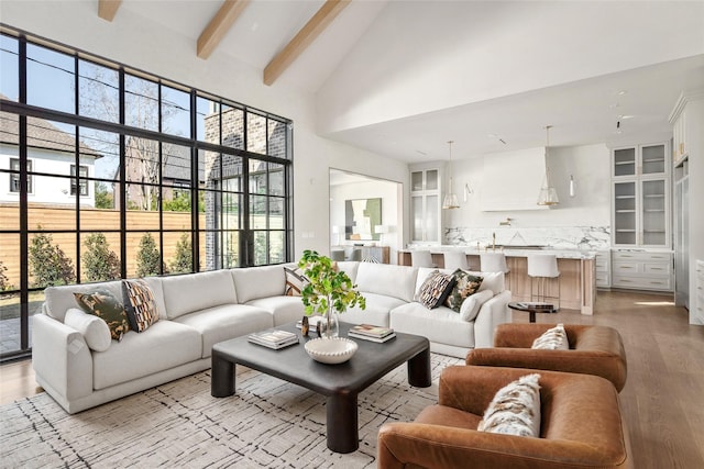 living room with high vaulted ceiling, light wood finished floors, beamed ceiling, and plenty of natural light