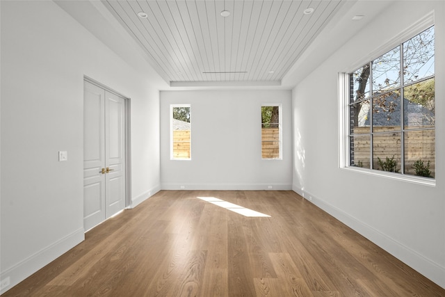 empty room featuring wooden ceiling, baseboards, and wood finished floors