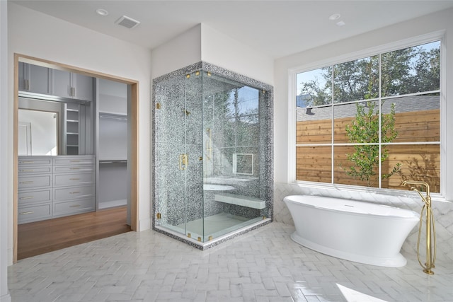 full bath with tile walls, a soaking tub, visible vents, and a shower stall