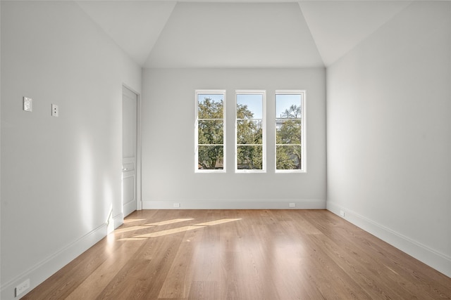 spare room featuring lofted ceiling, wood finished floors, and baseboards