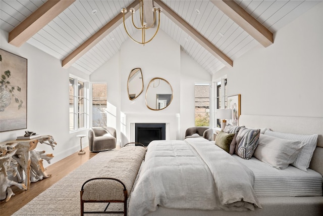 bedroom featuring beam ceiling, a fireplace, wood finished floors, high vaulted ceiling, and baseboards