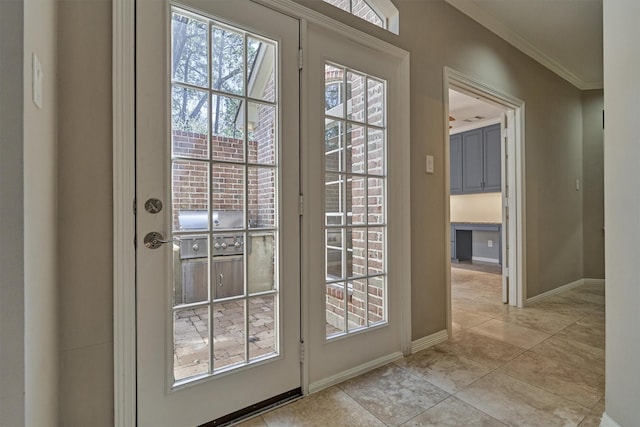 entryway with light tile patterned floors, ornamental molding, a healthy amount of sunlight, and baseboards