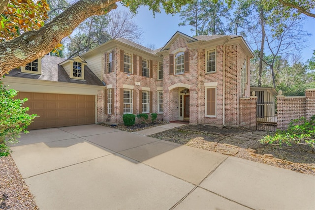 view of front facade featuring concrete driveway, brick siding, an attached garage, and a gate