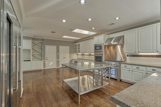 kitchen with a skylight, crown molding, visible vents, wall chimney range hood, and high quality appliances