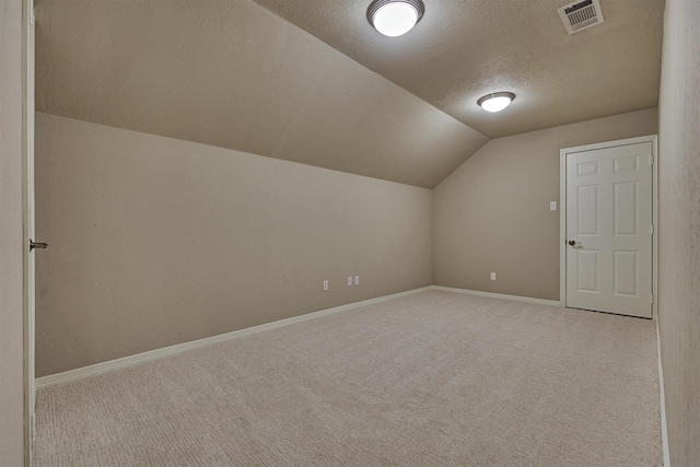 bonus room featuring baseboards, visible vents, vaulted ceiling, a textured ceiling, and carpet floors