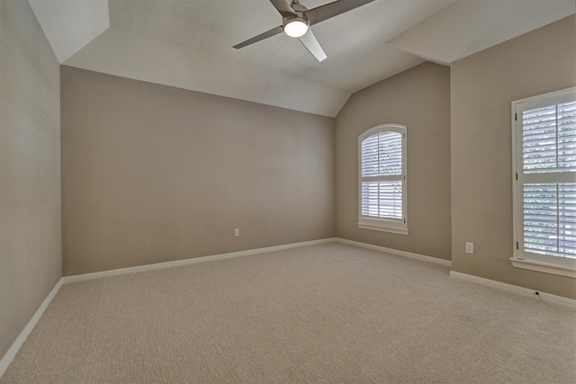 spare room with a wealth of natural light, light carpet, vaulted ceiling, and baseboards