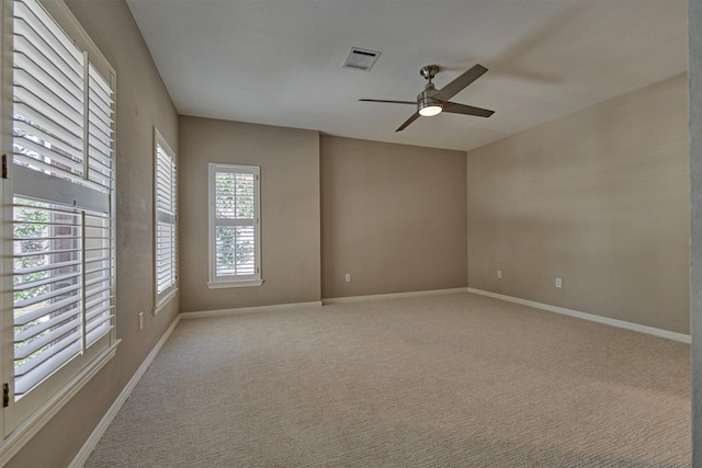 spare room featuring a ceiling fan, carpet, visible vents, and baseboards