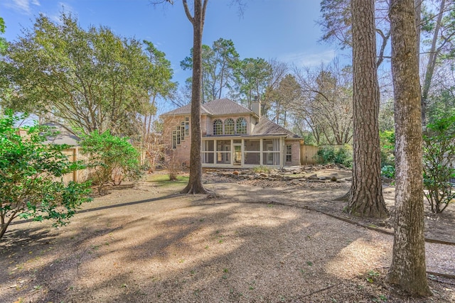 rear view of property featuring a chimney, fence, and a sunroom