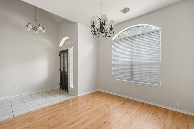 unfurnished room with baseboards, wood finished floors, visible vents, and an inviting chandelier