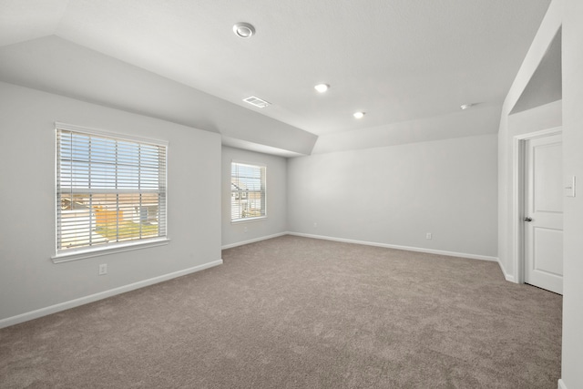 carpeted empty room with lofted ceiling, visible vents, and baseboards