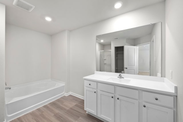 bathroom with recessed lighting, wood finished floors, vanity, visible vents, and a bath