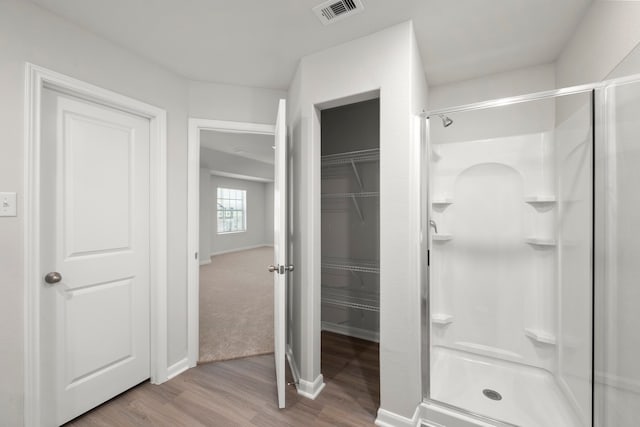 full bath with visible vents, a shower stall, and wood finished floors