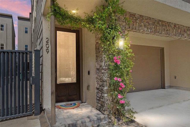 entrance to property with a garage and stucco siding