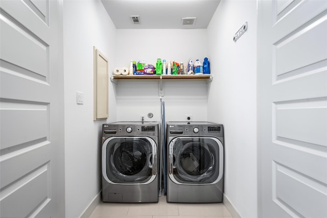 clothes washing area with baseboards, laundry area, visible vents, and washer and dryer