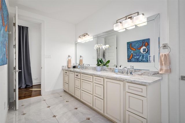 full bathroom featuring double vanity, tile patterned flooring, a sink, and baseboards