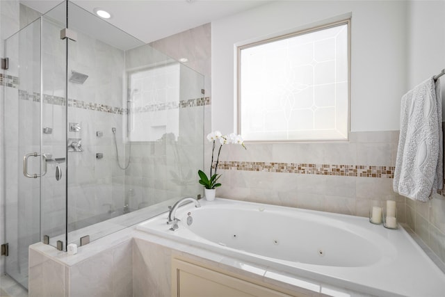 full bathroom featuring a whirlpool tub and a shower stall