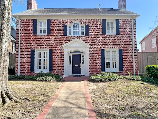 view of front of home featuring brick siding and a chimney